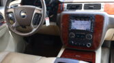 Inside view of a beige car cabin showing the steering wheel, wood-grain trim, and a built-in navigation/display screen.