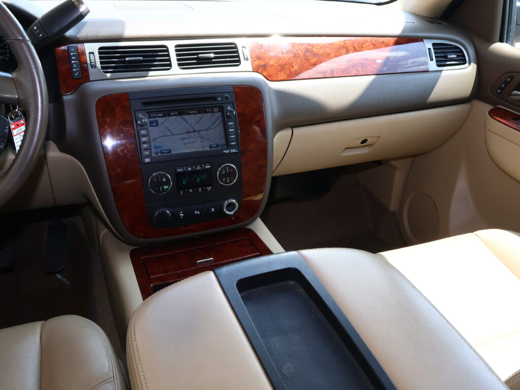 Beige car interior showing wood-grain dashboard trim, center console with navigation screen and climate controls.