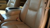 Tan leather car interior showing front seats, center console, and visible beige seatbelt in the passenger area.
