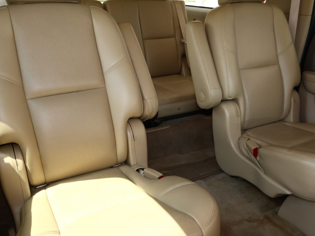 Beige leather car seats with captain's chairs and visible seat belts in a vehicle interior