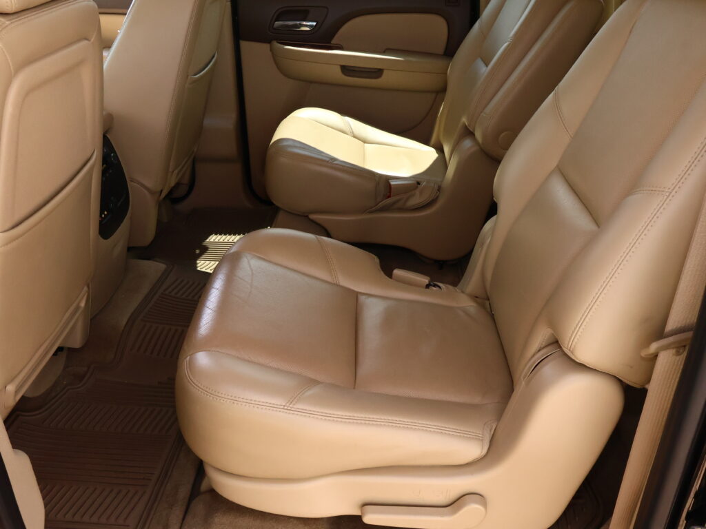 Beige leather car interior with a captain's chair in the middle row and a rear door panel visible.