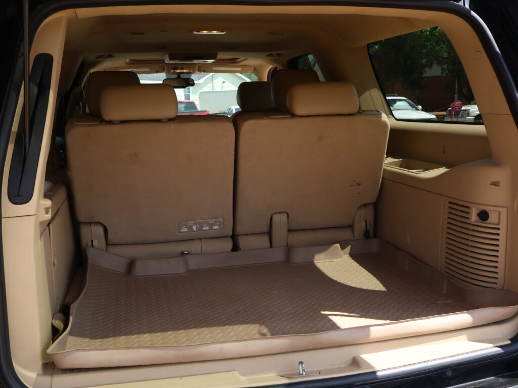 Interior of a beige SUV with the third-row seats upright and cargo area visible behind them.