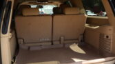 Interior of a beige SUV with the third-row seats upright and cargo area visible behind them.