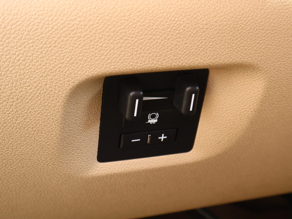 Close-up of a black two-button control on a beige textured car interior surface