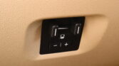 Close-up of a black two-button control on a beige textured car interior surface