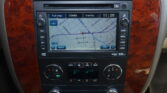 Car infotainment screen showing a GPS map with street names, surrounded by wood trim panels and climate controls below