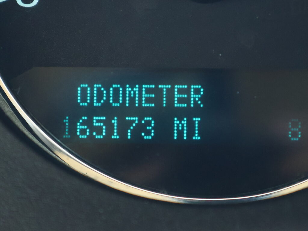 Digital odometer display on a car dashboard, showing the word ODOMETER with teal LED digits reading a mileage value.