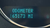 Digital odometer display on a car dashboard, showing the word ODOMETER with teal LED digits reading a mileage value.