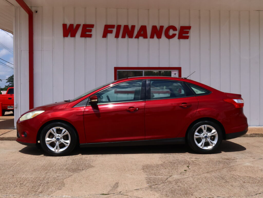 Red sedan parked in front of a white building with a bold red 'WE FINANCE' sign on the wall.