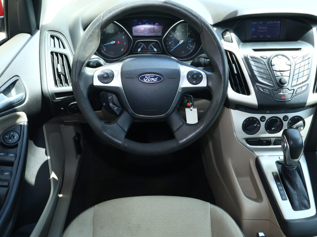 Interior view of a Ford car dashboard with steering wheel, instrument cluster, and center console controls visible from the driver’s seat.