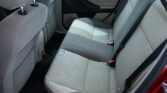 Back seat interior of a car with light gray fabric upholstery, showing two seats and seat belts along the side door panel.