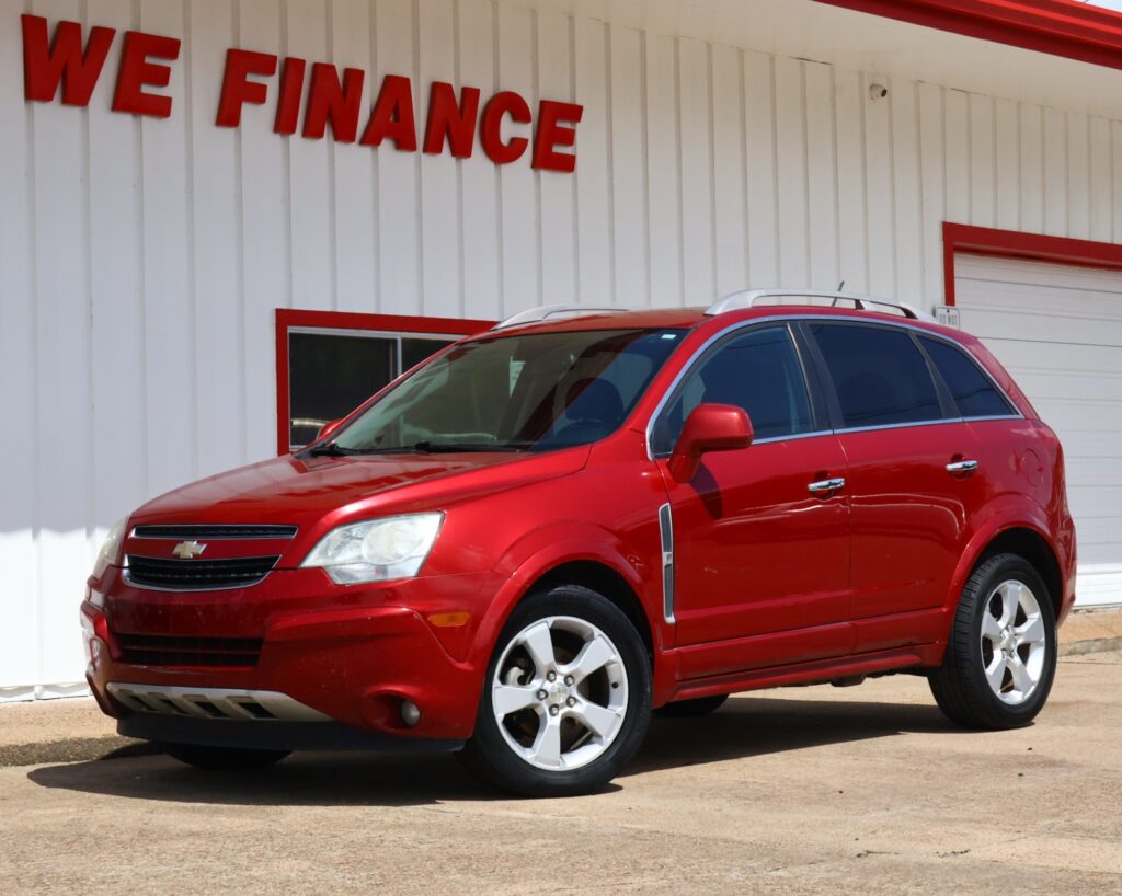 Red Chevrolet SUV parked in front of a white building with a bold red 'WE FINANCE' sign at a dealership.