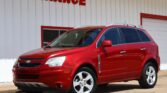 Red Chevrolet SUV parked in front of a white building with a bold red 'WE FINANCE' sign at a dealership.
