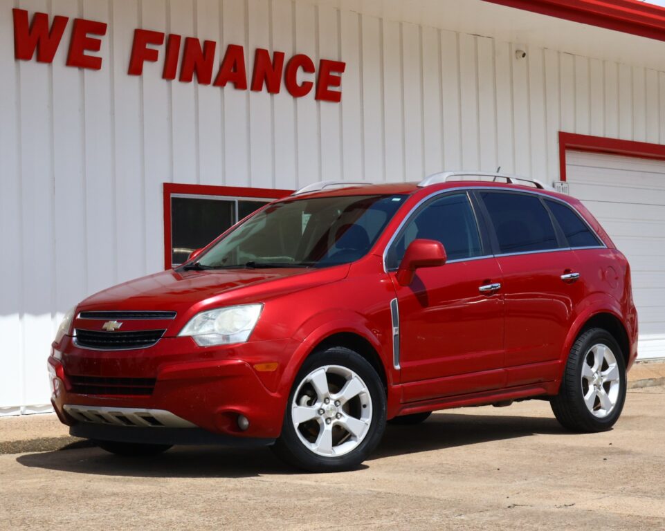 Red Chevrolet SUV parked in front of a white building with a bold red 'WE FINANCE' sign at a dealership.
