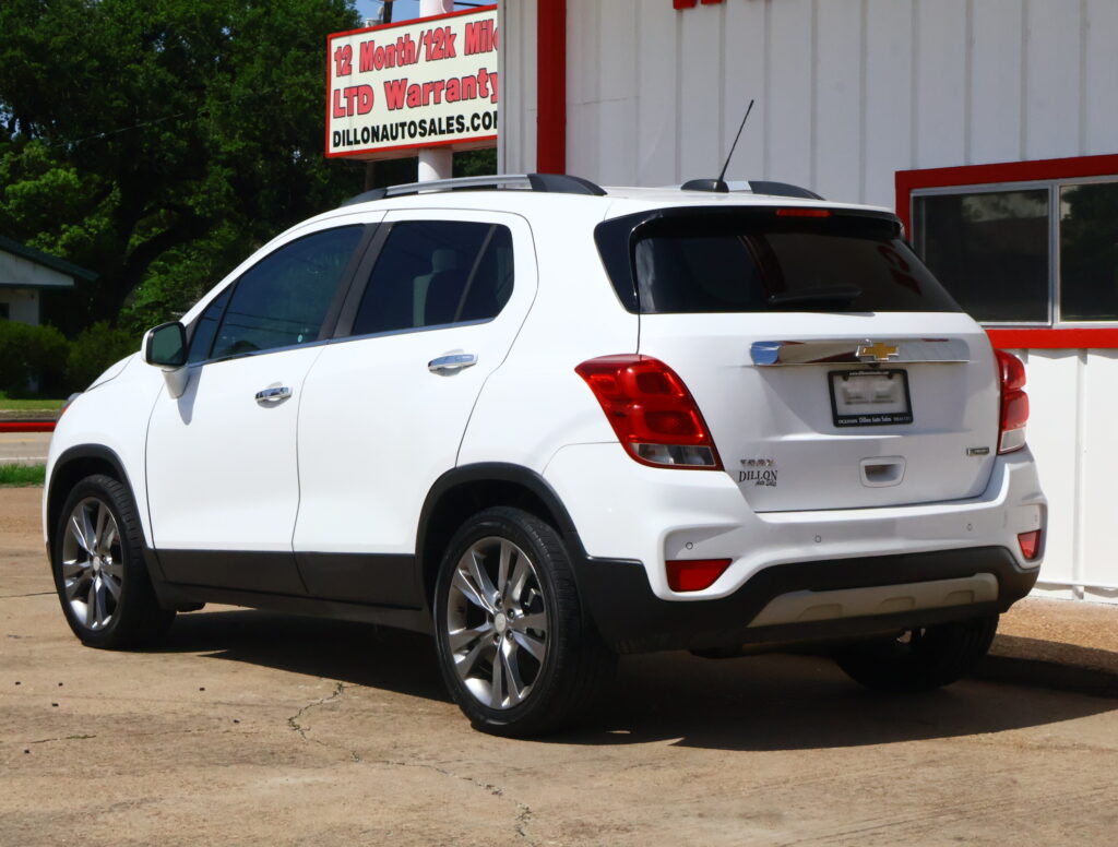 White SUV parked in front of a dealership building with a sign reading 'Dillon Auto Sales' visible on the roof area and rear badge.