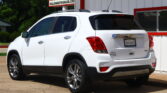 White SUV parked in front of a dealership building with a sign reading 'Dillon Auto Sales' visible on the roof area and rear badge.
