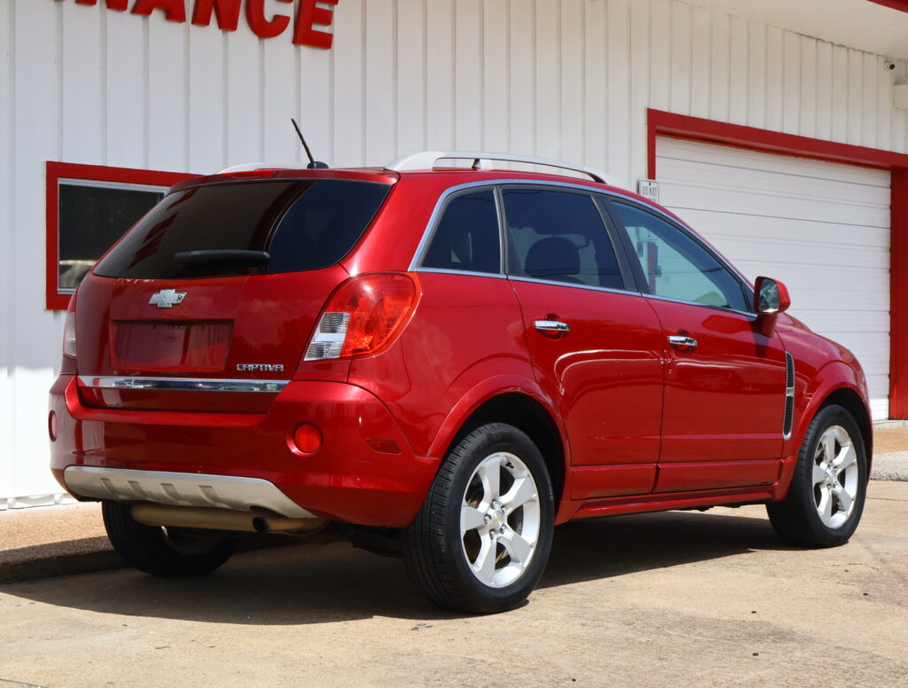 Red Chevrolet Captiva SUV parked at a slight angle in front of a white building with red trim.