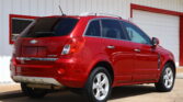 Red Chevrolet Captiva SUV parked at a slight angle in front of a white building with red trim.
