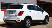 White SUV parked outside a white building with red trim, shown from the rear and passenger side.