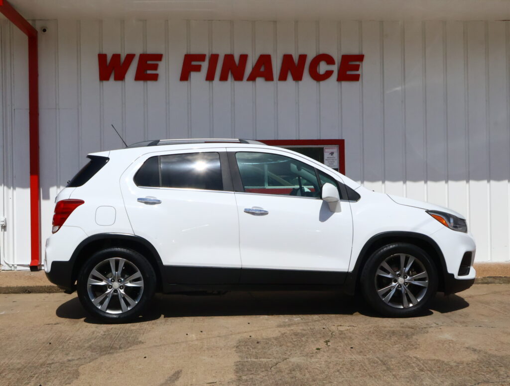 White SUV parked in front of a white wall with large red 'WE FINANCE' letters.