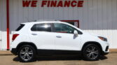 White SUV parked in front of a white wall with large red 'WE FINANCE' letters.