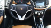 Close-up of a Chevrolet steering wheel with brown leather seats and an digital instrument cluster in a car cabin