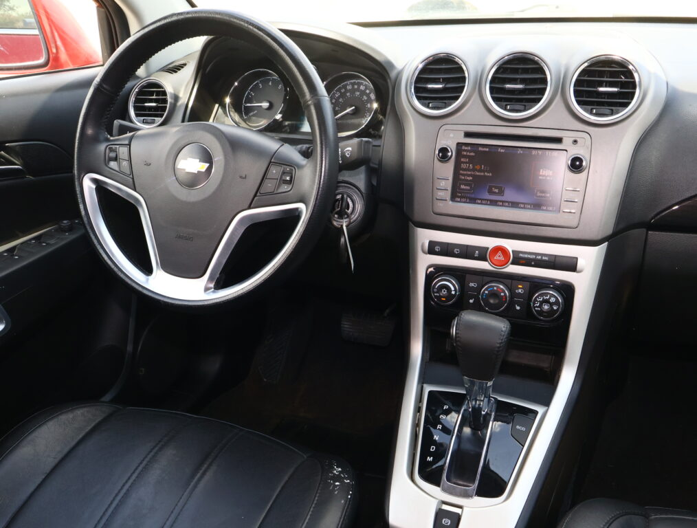 Dashboard interior: steering wheel in foreground, instrument cluster behind, and central touchscreen display with round air vents nearby