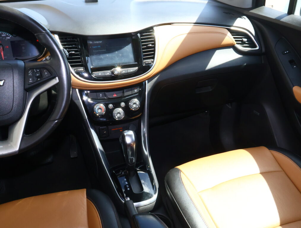 Interior of a car showing the center console with touchscreen, gear shifter, and tan leather seats