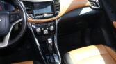 Interior of a car showing the center console with touchscreen, gear shifter, and tan leather seats
