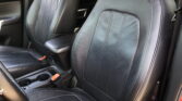 Front interior of a car showing black leather seats and center console with cup holders.