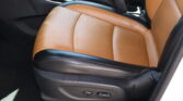 Close-up view of a tan leather car seat with black trim and visible seat adjustment controls on the side of the seat base.