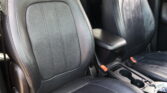 Black leather car seats with a center console and orange seat belt buckles visible between the front seats.