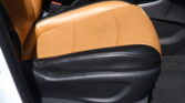 Tan leather car seat with black base and visible red seat-belt buckle in a vehicle interior front row.