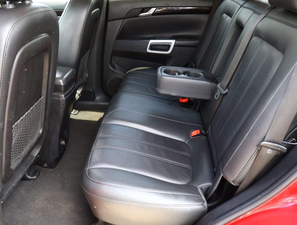Rear row of a car with black leather seats; center armrest folded down showing two cup holders in the middle.