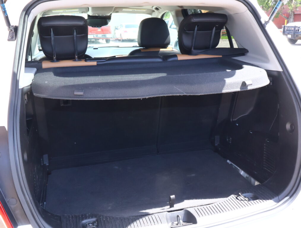 Rear cargo area of a white SUV with seats upright and a dark cargo cover in place