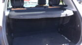 Rear cargo area of a white SUV with seats upright and a dark cargo cover in place