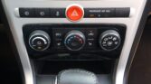 Center console of a car: hazard button flanked by climate control buttons and a leather gear shift boot below.