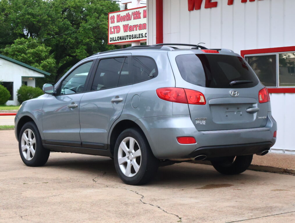 Gray Hyundai SUV parked in front of a white dealership building with red trim.