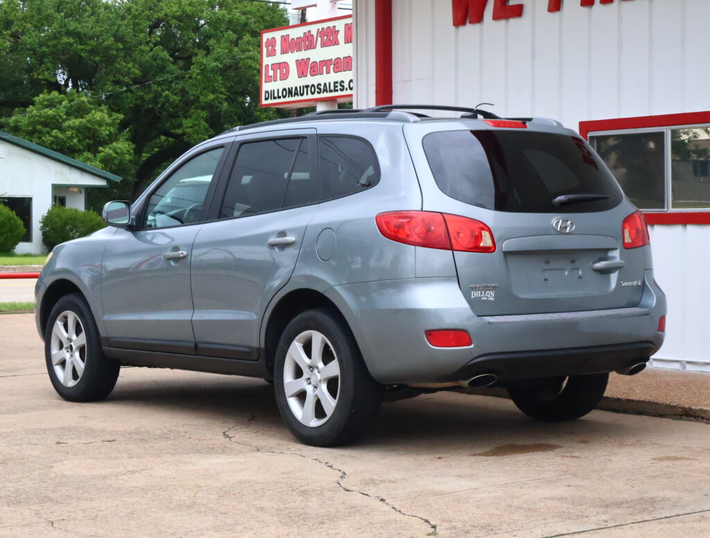 Gray Hyundai SUV parked in front of a white dealership building with red trim.