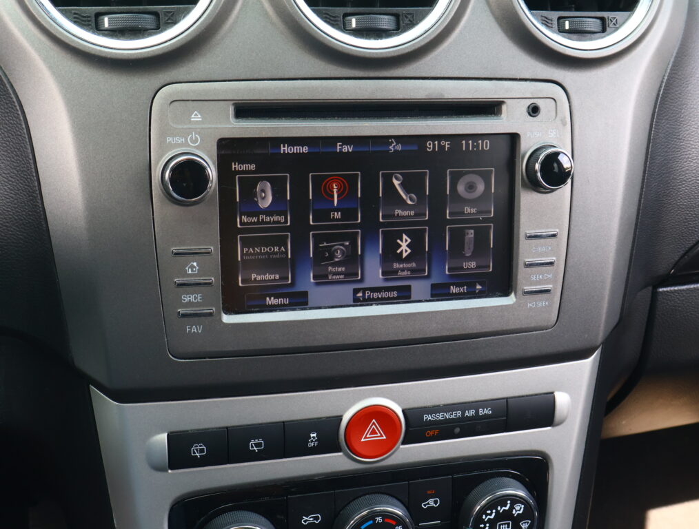 Car infotainment touchscreen showing Now Playing, FM, Phone, and other apps on a dashboard UI