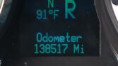 Close-up of a digital car odometer display showing mileage in miles on a dark dashboard.