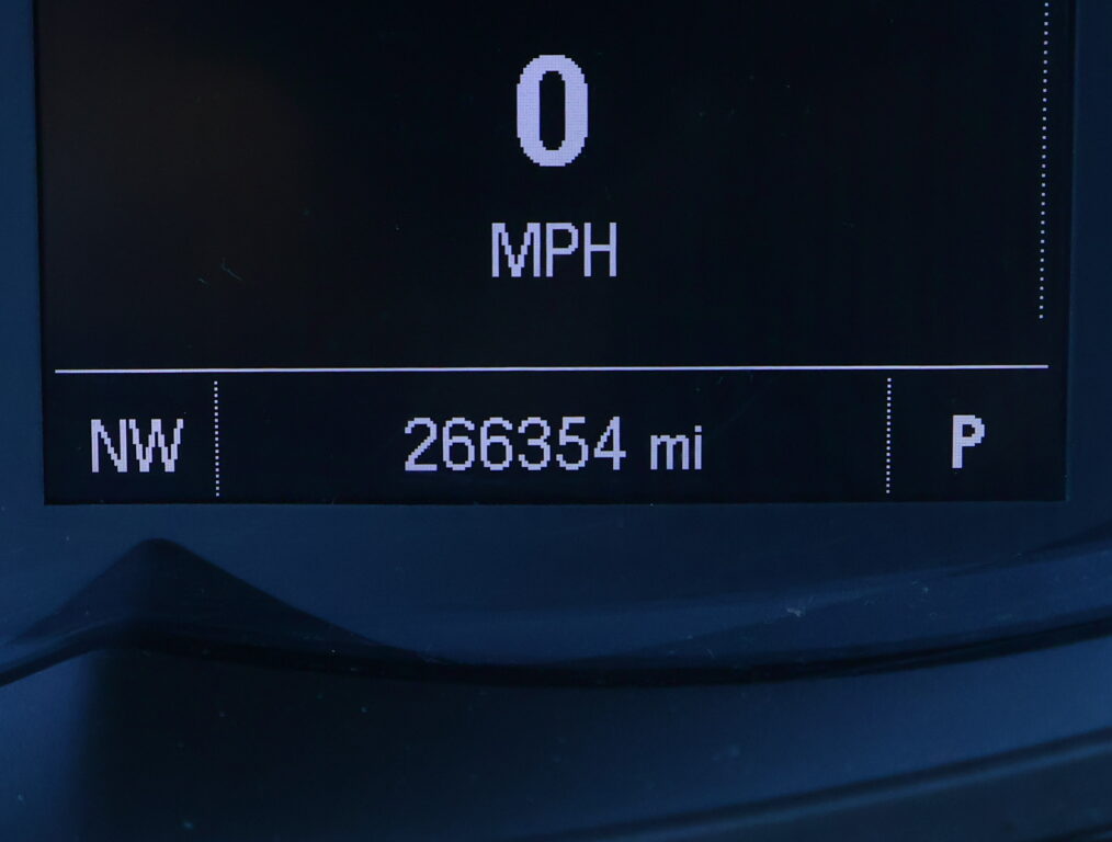Car dashboard readout showing current speed 0 MPH with NW as direction and an odometer reading of 266,354 miles