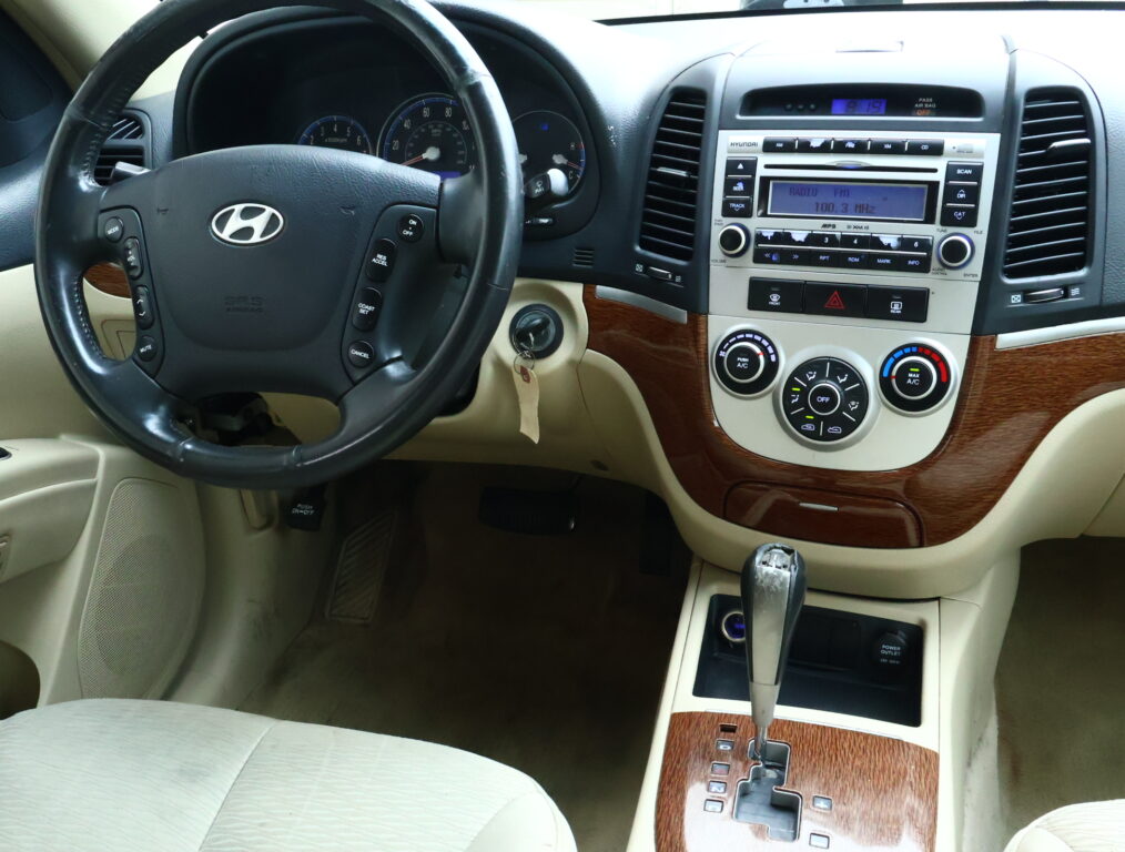 Interior view of a car cockpit showing steering wheel, instrument cluster, and center console with wood trim.