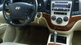 Interior view of a car cockpit showing steering wheel, instrument cluster, and center console with wood trim.