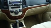 Center dashboard of a car showing radio, climate controls, and wood-grain trim with beige upholstery