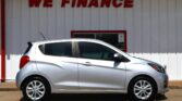 Silver hatchback parked in front of a white wall with a red 'WE FINANCE' sign above it.