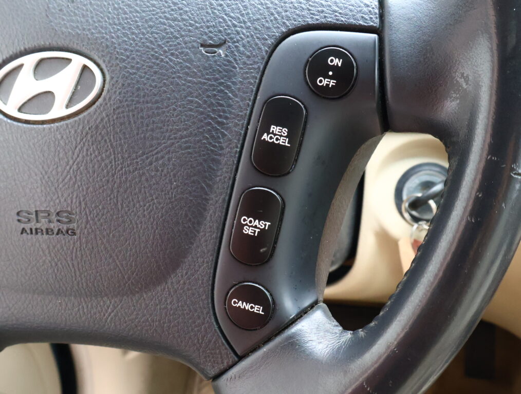 Close-up of a Hyundai steering wheel showing cruise control buttons: ON/OFF, RES/ACCEL, COAST/SET, and CANCEL along the side.