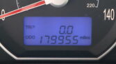 Close-up of a car dashboard: analog speedometer with a red needle around 20 mph, and a blue digital display showing TRIP 0.0 and an odometer reading about 119,955 miles.