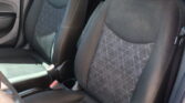 Inside a car showing the dark fabric front seats with geometric stitching and a center console area nearby, in a muted gray interior.