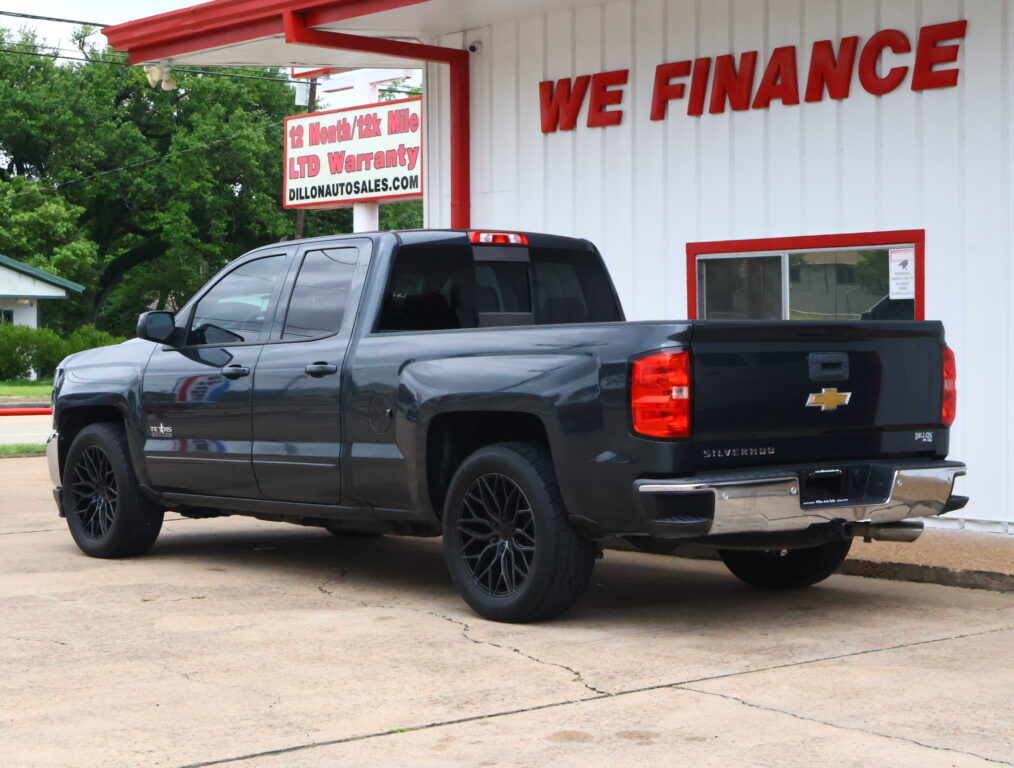 Black Chevrolet Silverado pickup truck parked in front of a white building with a red 'WE FINANCE' sign in the background.